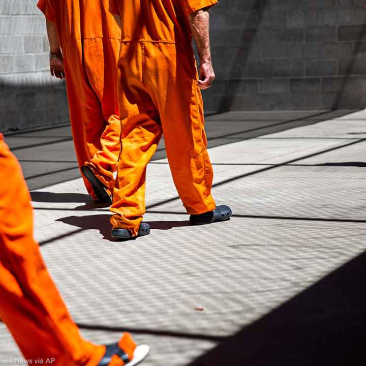 A group of incarcerated people walking a concrete yard