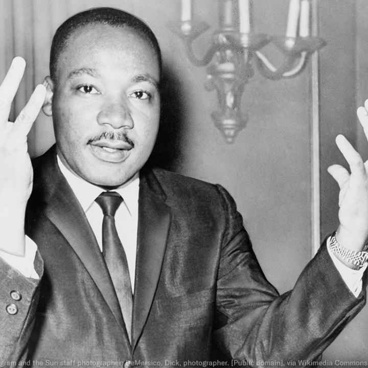 Rev. Martin Luther King, head-and-shoulders portrait, seated, facing front, hands extended upward, during a press conference